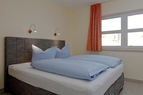 a bedroom with a bed with blue pillows and a window at Vineta Ferienpark Usedom in Koserow