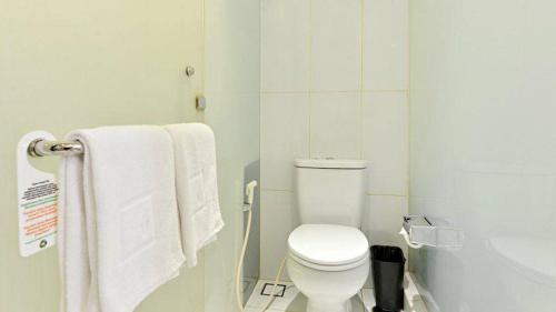 a white bathroom with a toilet and towels at V Hotel Tebet in Jakarta