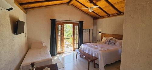 a bedroom with a bed and a sliding glass door at Chalés e Suítes Campos de São João in Palmeiras