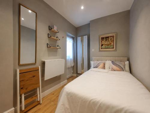 a bedroom with a bed and a dresser and a mirror at Luxury Budget Flat in Middlesex in Colindale