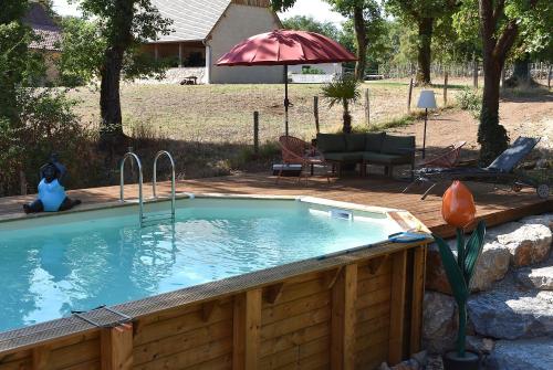 a swimming pool in a backyard with an umbrella at Trésor en Bois Chambres d'Hôtes in Autoire