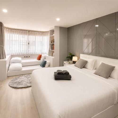 a white bedroom with a large bed and a couch at Sweet room in Nimnan in Chiang Mai