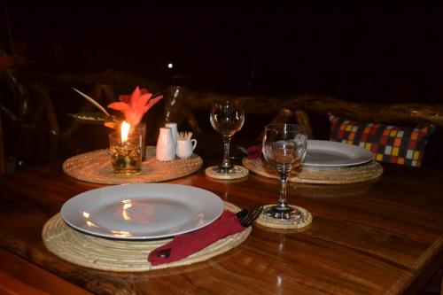 Camiguin Volcan Beach Eco Retreat & Dive Resort في مامباجاو: طاولة خشبية عليها لوحات واكواب للنبيذ