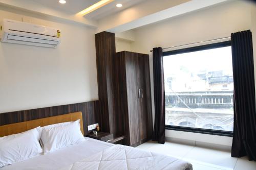 a bedroom with a bed and a large window at Hotel Shreeji Palace in Ābu Road