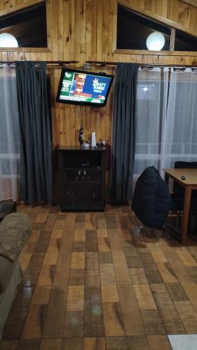 a living room with a flat screen tv and a table at Cabañas El Rincon del Sur in Colaco