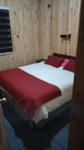 a bedroom with a large bed with red sheets at Cabañas El Rincon del Sur in Colaco