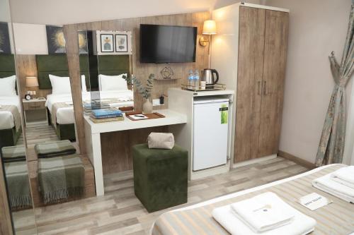a hotel room with a bed and a desk with a television at Alkış Otel in Iğdır