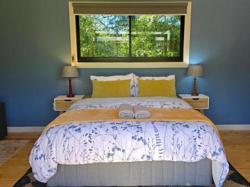 a bedroom with a bed with two lamps and a window at Moss & Moon Cabins in Stormsrivier
