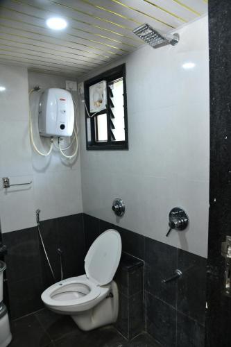 a bathroom with a toilet and a window at Hotel Shreeji Palace in Ābu Road