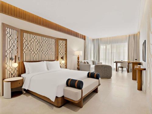 a bedroom with a large white bed and a chair at Mercure Abu Dhabi Downtown in Abu Dhabi