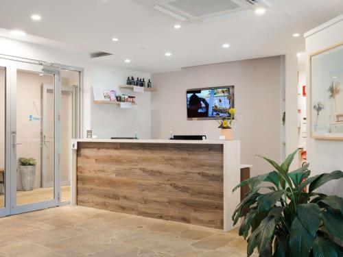 a lobby with a wooden bar with a tv on the wall at The Sebel Byron Bay in Byron Bay