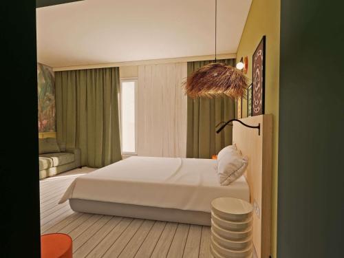 a bedroom with a white bed and a chair at Ibis Styles Vannes Pte Golfe in Vannes