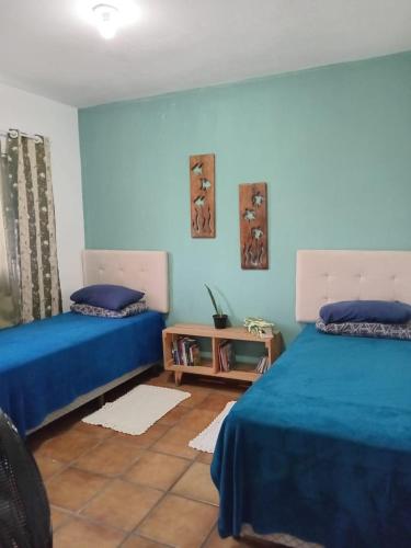 a bedroom with two beds and a table in it at KaDinizHouse in Caraguatatuba