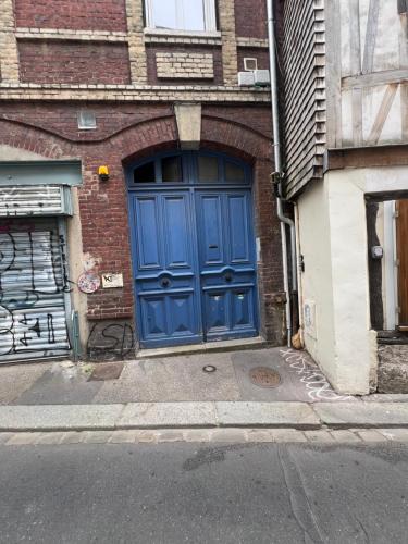 a blue door on the side of a brick building at Le petit nid rouennais in Rouen