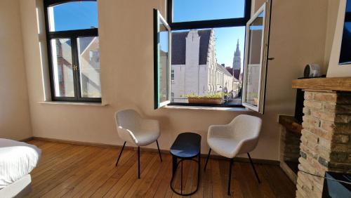 a room with three chairs and a bed and windows at Suite Stays Bruges - Pandreitje 6 in Bruges