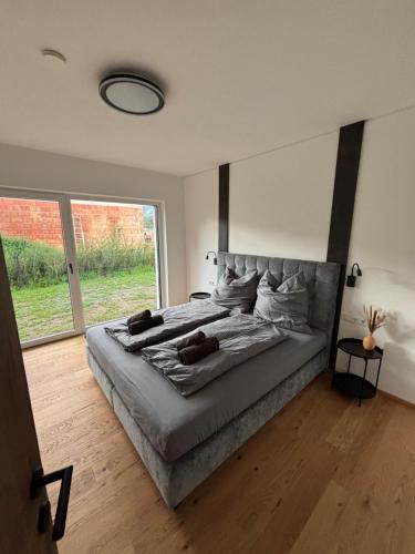 a large bed in a bedroom with a large window at Alpenoase Ennstal in Ennsling