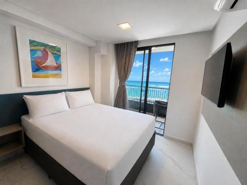 a bedroom with a bed and a balcony with the ocean at Smeralda del Mare by AFT in Porto De Galinhas