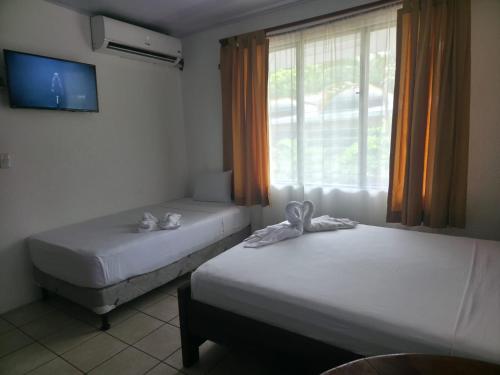 two beds in a room with a window at Centro Vacacional Villas Costa Jaco in Jacó