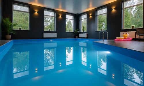 a swimming pool in a house with windows at Lapsiņmuiža Pool House - Pool, Sauna & Hot-tub included in Dzedri