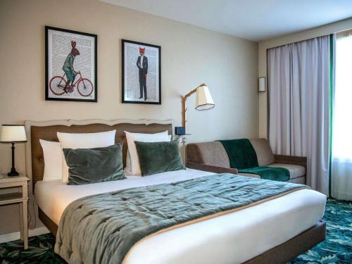 a hotel room with a large bed and a couch at Hotel Novotel Domaine de Maffliers - Paris Val-d'Oise in Maffliers