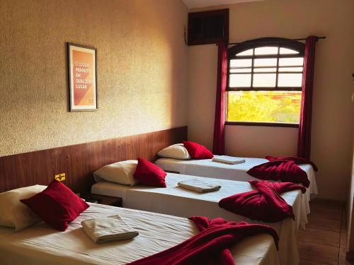 a room with three beds with red pillows on them at Fazenda Itaygua Hotel in Ribeirão Preto