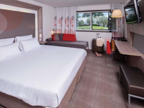 a hotel room with a large bed and a couch at Novotel Nantes Carquefou in Carquefou