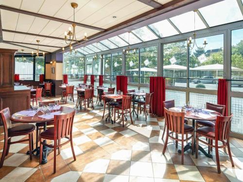 a dining room with tables and chairs and windows at ibis Chartres Ouest Luce in Chartres