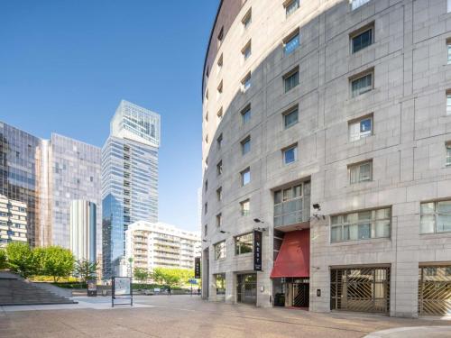 a large stone building in a city with tall buildings at Nest Hotel Paris la Défense - MGallery Collection in Puteaux
