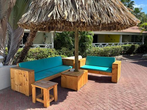 two benches and an umbrella and a stool under it at Blue Marlin Apartments, nabij Mambo Beach in Willemstad