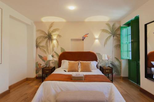a bedroom with a large bed and palm trees at Casa Aura Hotel in Bogotá