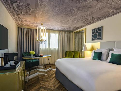 a hotel room with a large bed and a desk at Le Louis Hotel Versailles Château - MGallery Collection in Versailles