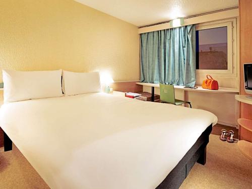 a large white bed in a room with a window at ibis Augsburg Hauptbahnhof in Augsburg