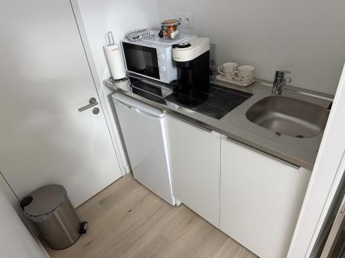 a small kitchen with a sink and a microwave at L'Escapade Caramanaise in Caraman