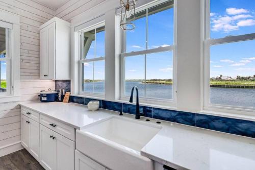 a kitchen with a sink and two windows at Nauti Captain in Port Aransas