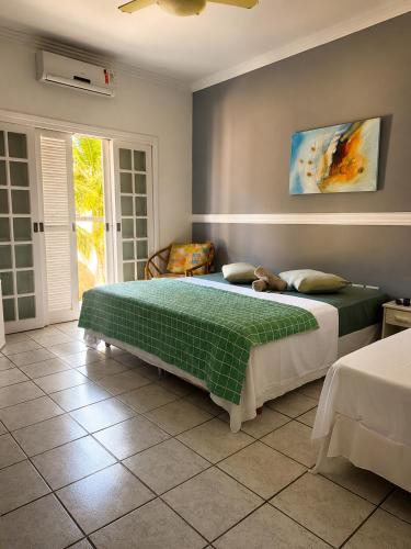 a bedroom with a large bed with a green blanket at GrandMaré Hotel in Peruíbe