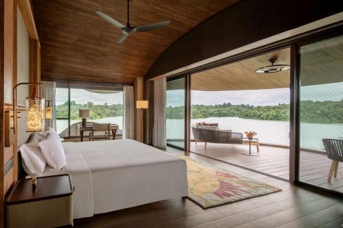 a bedroom with a bed and a view of the water at Mandai Rainforest Resort by Banyan Tree in Singapore