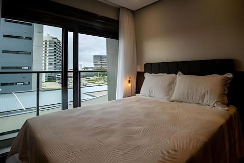 a bedroom with a large bed and a large window at Loft 406 Inn - Parque Una + garagem in Pelotas