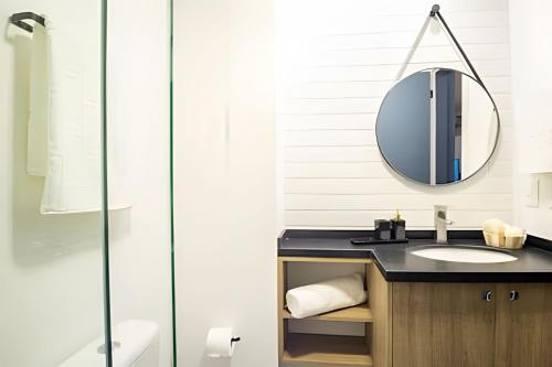 a bathroom with a sink and a mirror at Loft 406 Inn - Parque Una + garagem in Pelotas