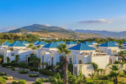 a large white house with blue roofs at Banyan Tree Tamouda Bay in Fnidek