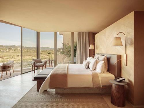 a bedroom with a bed and a large window at Banyan Tree Veya, Valle de Guadalupe in Valle de Guadalupe
