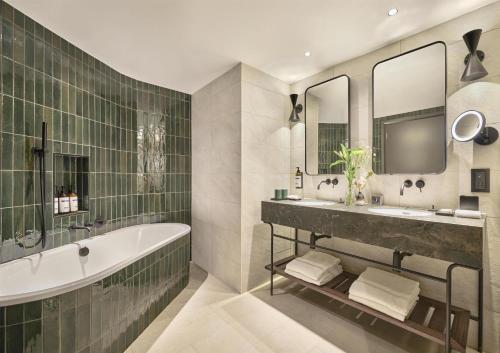 a bathroom with a tub and a sink and mirror at Hyatt Regency London Blackfriars in London