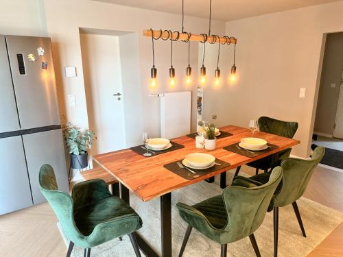 a dining room with a wooden table and green chairs at JUPAS - Premium Apartments Trier in Trier