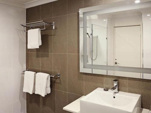 a bathroom with a sink and a mirror and towels at Novotel Vines Resort Swan Valley in Upper Swan