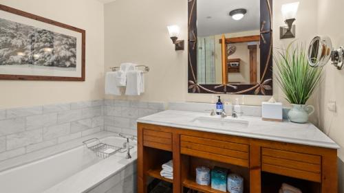 a bathroom with a sink and a tub and a mirror at 147 Studio Spruce Peak Lodge at Stowe Mt Resort Sleeps 4 in Stowe