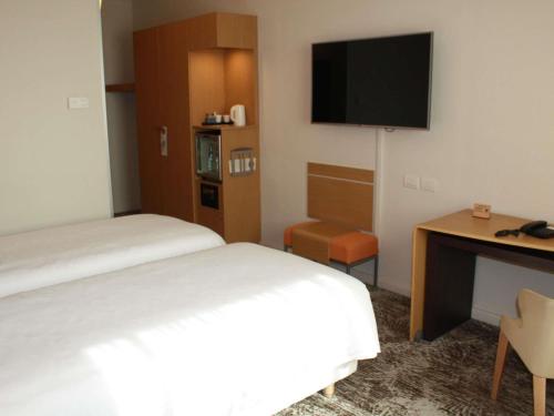 a hotel room with a bed and a desk and a television at Novotel Roma Est in Rome