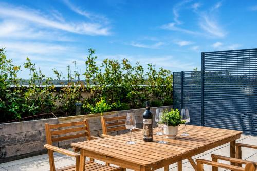 a wooden table with a bottle of wine and wine glasses at City Penthouse - Roof Terrace & Free Parking in Beeston Hill