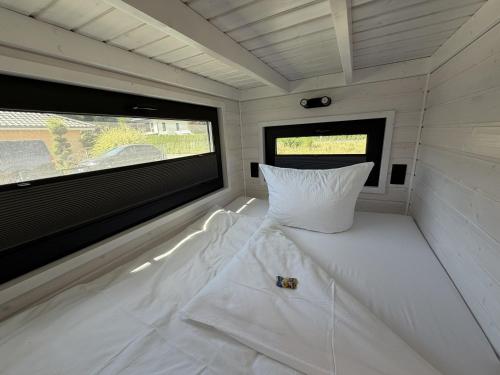 a white bed in a room with a window at Tiny House WICA in Königs Wusterhausen
