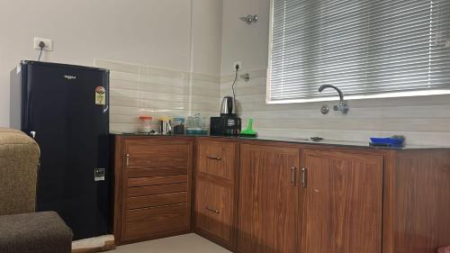 a kitchen with a black refrigerator and wooden cabinets at Stay near to temple 240m in Guruvāyūr