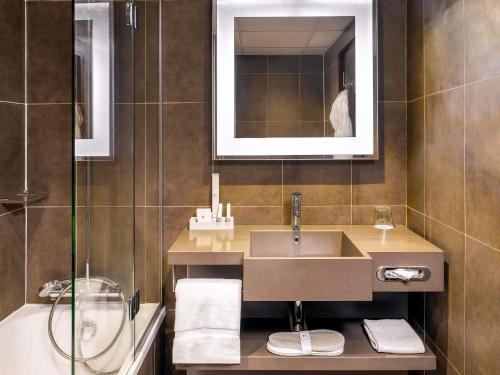 a bathroom with a sink and a mirror and a tub at Novotel Port Harcourt in Port Harcourt