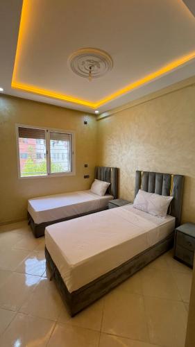 two beds in a room with two windows at Appartement Agadir in Inezgane